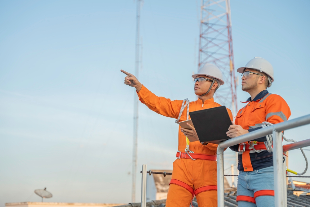 Hombre vestido de naranja señalando torre